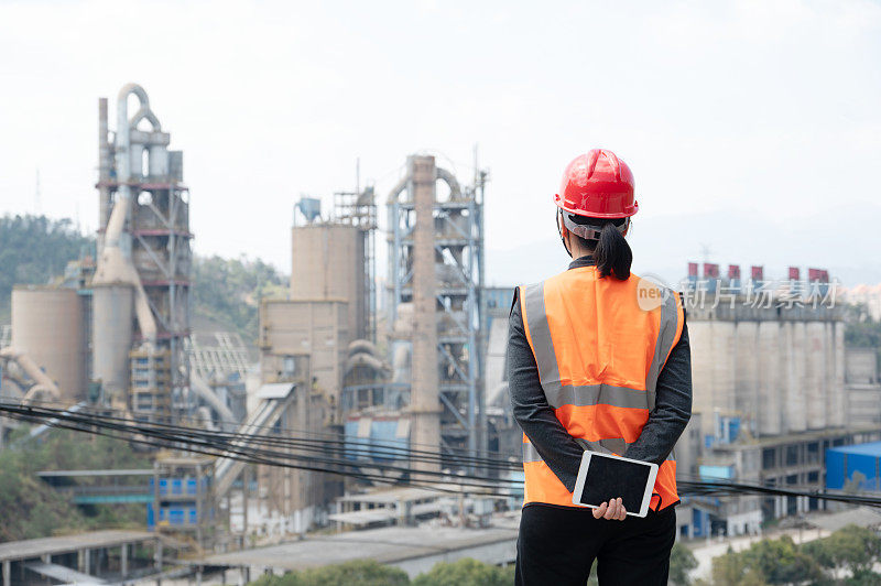 A female engineer looked at the cement factory in the distance with the camera on her back